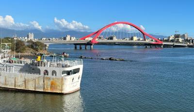 Photo of Taiwan fishing vessel docked at Donggang Harbor with red arched bridge in background