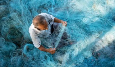Thai man making fishing net - photo by Shutterstock